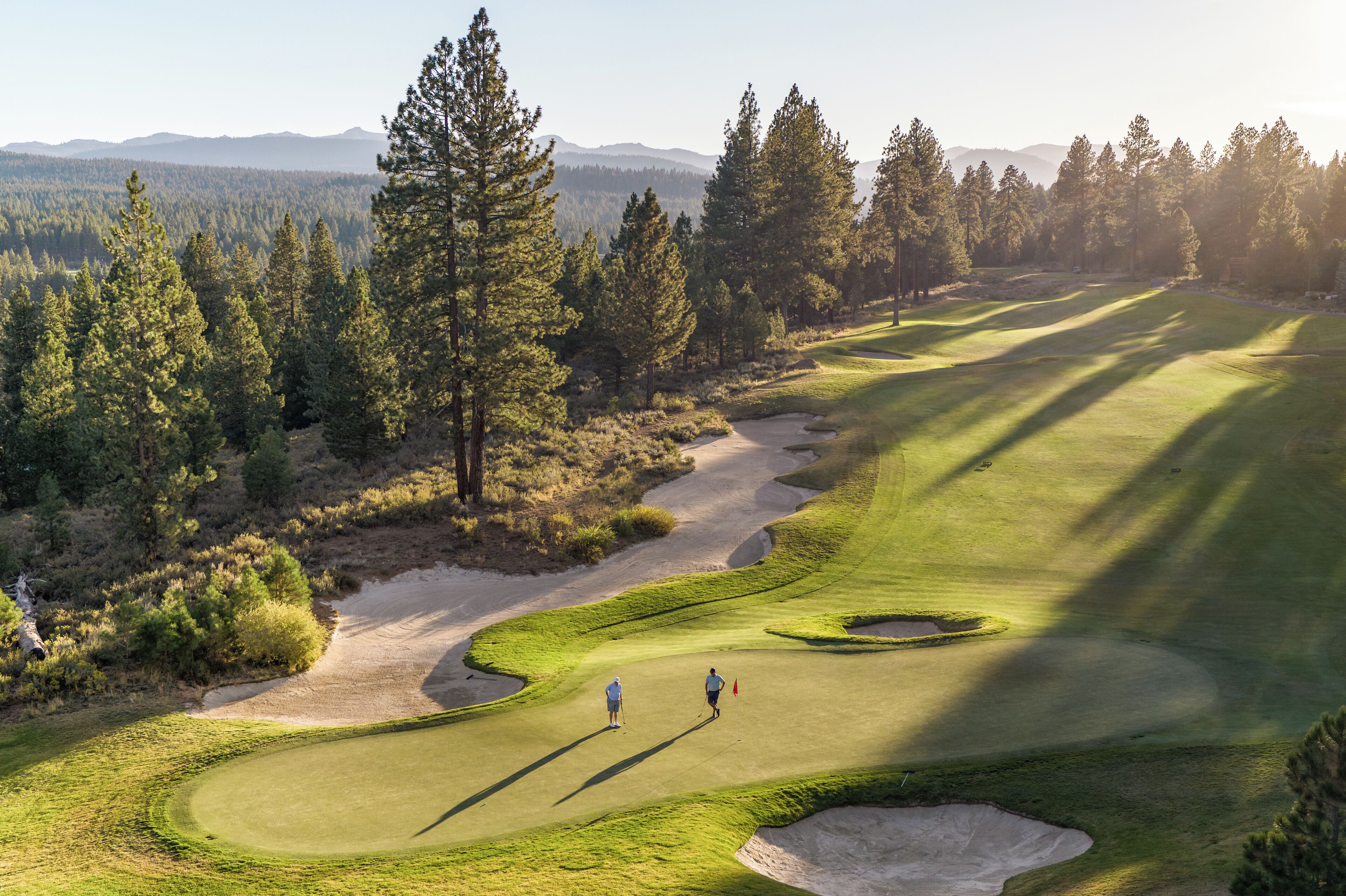 A golf course with a well-maintained fairway, sand bunkers, and a flagstick.