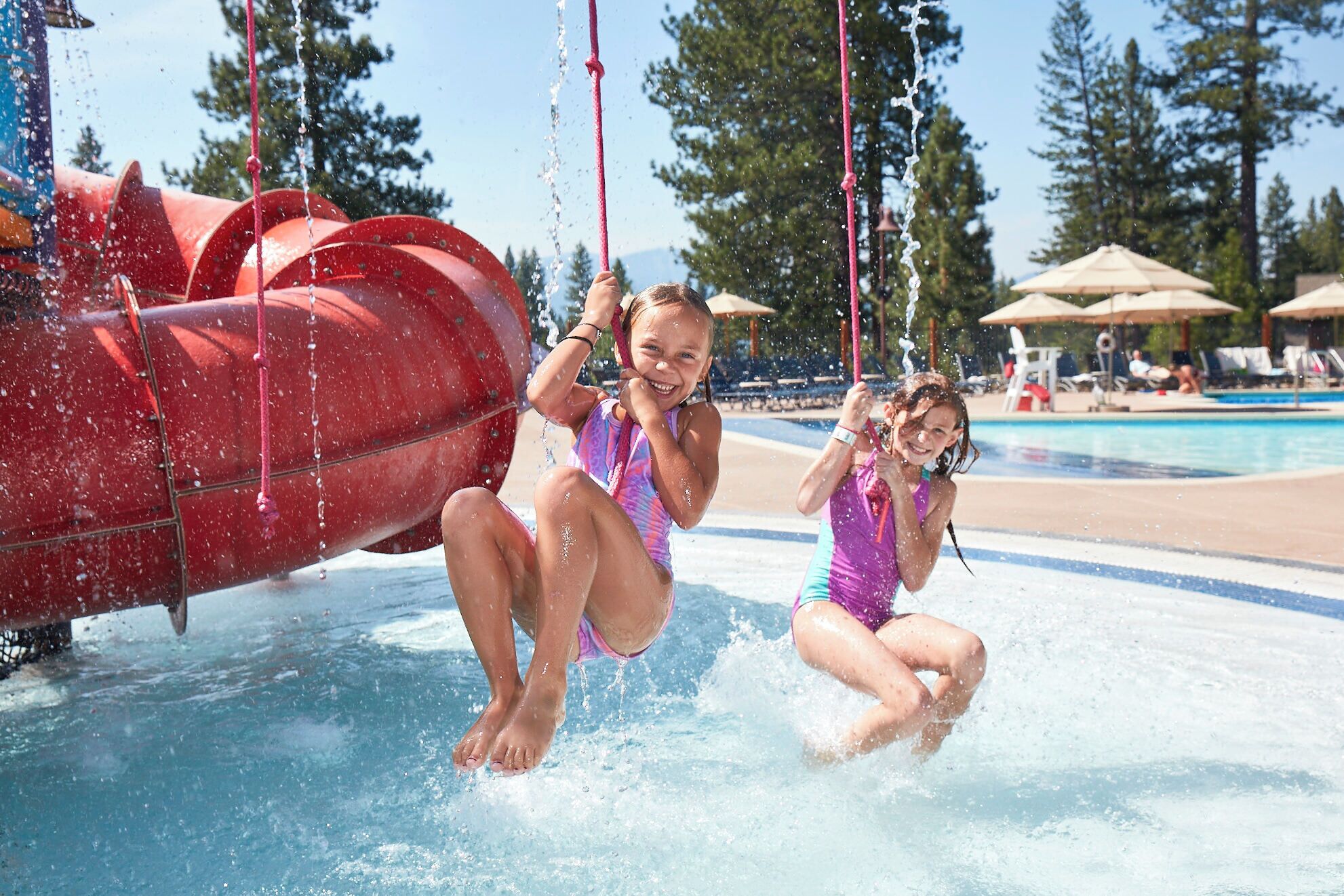 Un parc aquatique doté d’un grand toboggan rouge et d’un espace piscine.