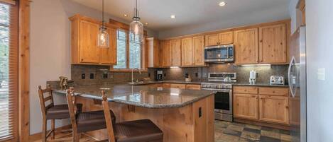 A spacious kitchen with wooden cabinets, a granite countertop, and modern appliances including a microwave and oven.