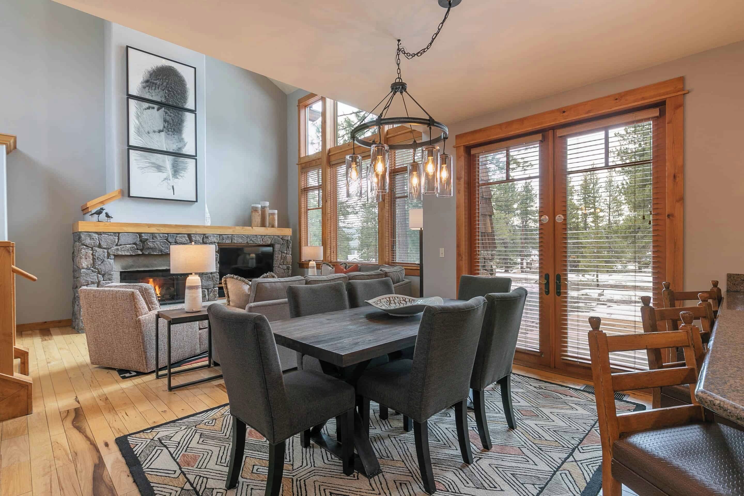 Una sala de estar moderna con chimenea, comedor y ventanas grandes.