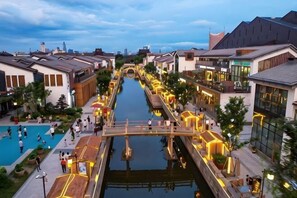 A canal-side hotel with a swimming pool, wooden walkways, and modern buildings. - weige Boutique Hotel (Shaoxing)