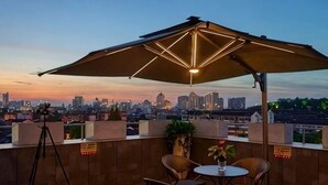 Eine Dachterrasse mit Blick auf die Stadt, ein Tisch mit Stühlen und ein großer Sonnenschirm.