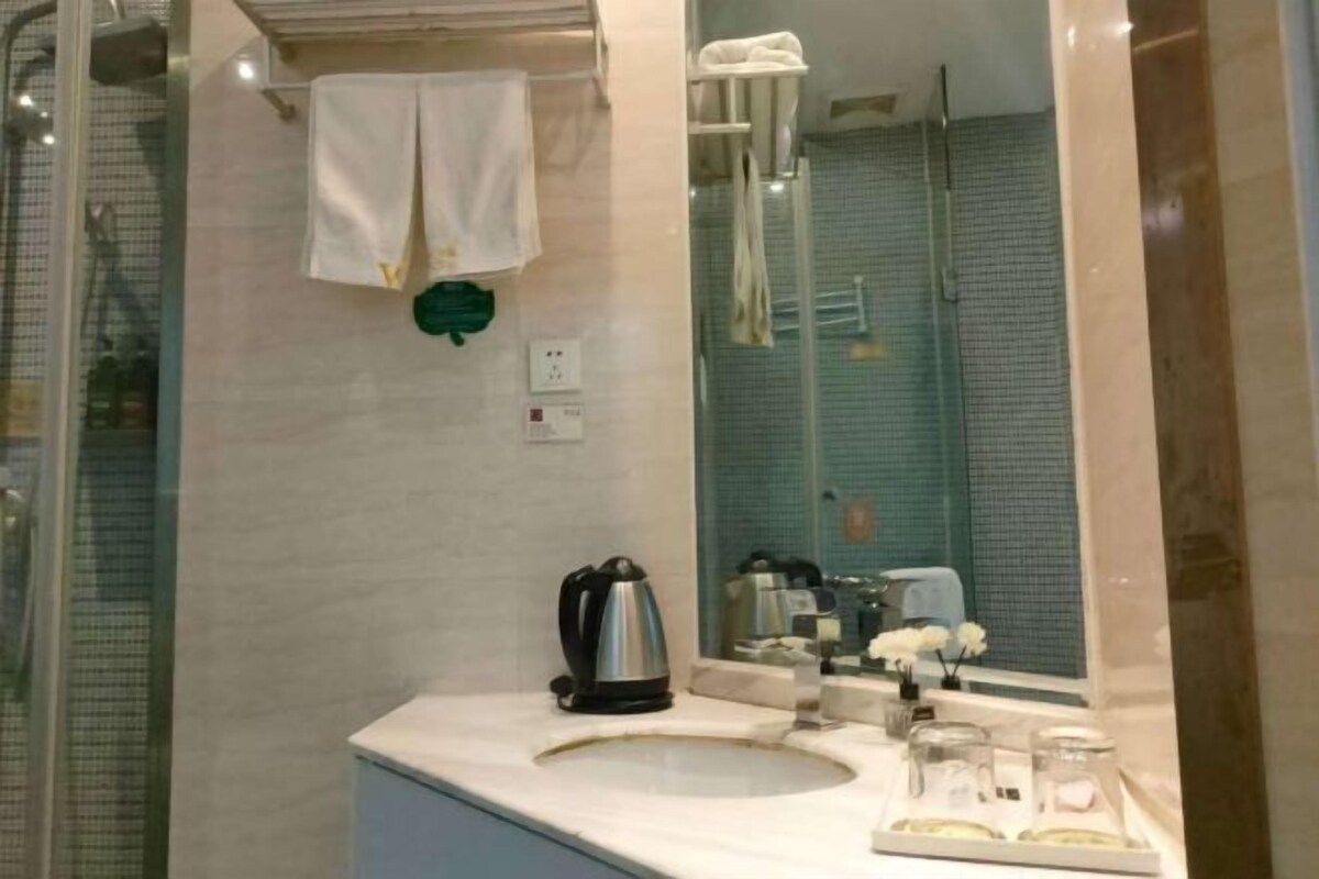 A bathroom with a sink, a mirror, a towel rack, and a shower area.
