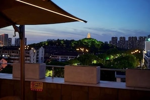 A cityscape at dusk with a prominent golden pagoda on a hill, surrounded by residential buildings and greenery. - weige Boutique Hotel (Shaoxing)