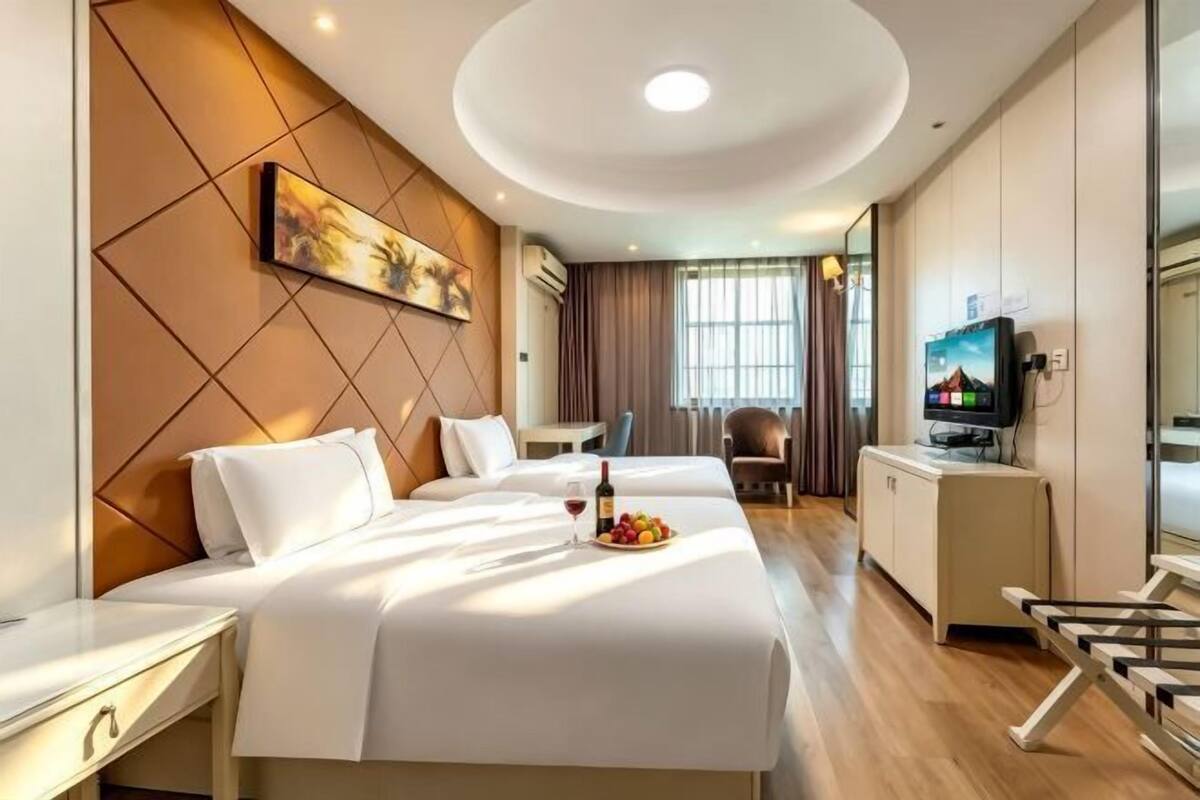 Quarto de hotel com cama, secretária, televisão e área de refeições.