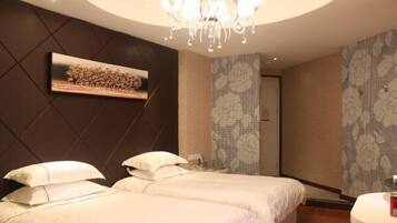 A hotel room with two beds, a chandelier, a painting on the wall, and patterned wallpaper.