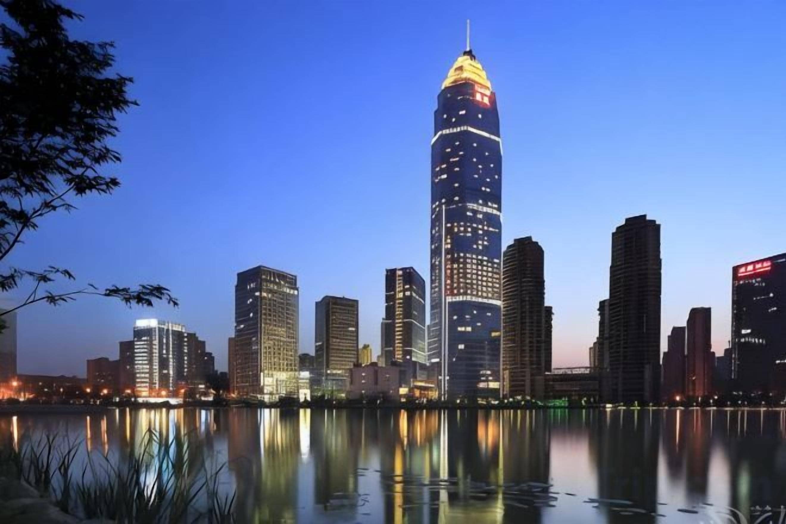 A city skyline with a prominent tower reflecting on water.