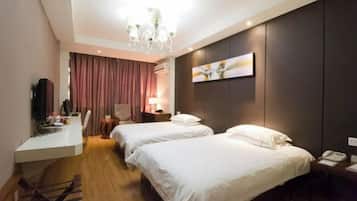 Quarto de hotel com duas camas, uma escrivaninha, uma cadeira, televisão e um candelabro.