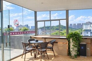 A balcony with a table and chairs, a potted plant, and a view of a cityscape. - weige Boutique Hotel (Shaoxing)