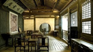 Ein traditioneller Raum mit Tatami-Bodenbelag, Holzmöbeln und großen Fenstern.