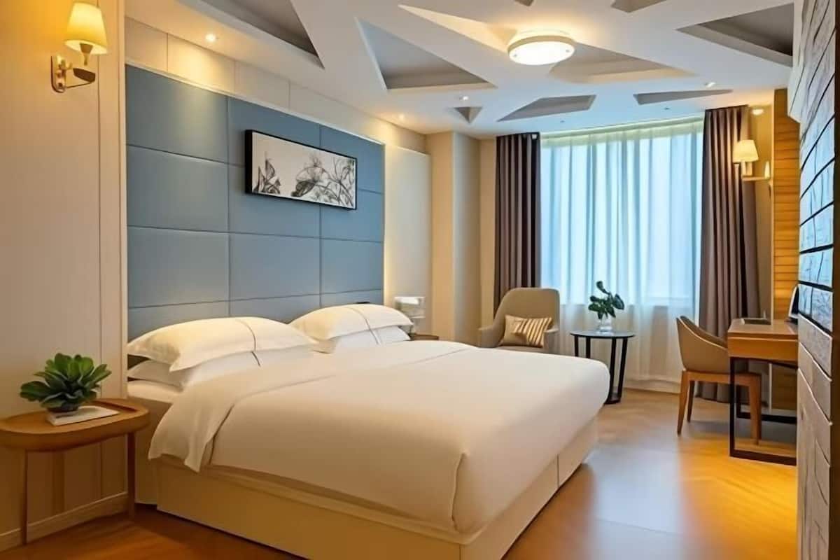 Quarto de hotel moderno com uma cama grande, uma escrivaninha e uma cadeira.
