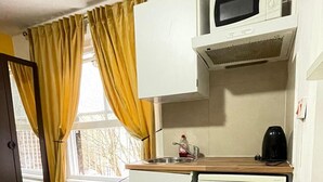 A compact kitchenette with a microwave, a sink, and a coffee maker. - Studio Sleeps 2 With Internet Access (London)