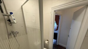 A bathroom with a glass shower enclosure, a toilet, and a visible door leading to another room. - Studio Sleeps 2 With Internet Access (London)