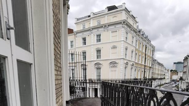 A narrow concrete pathway with a metal fence on one side and a building with multiple windows and balconies on the other. - Apartment Sleeps 2 With Balcony (London)