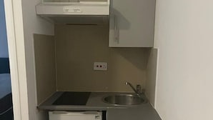 A compact kitchenette with a built-in refrigerator, a sink, and a countertop. - Apartment Sleeps 2 With Balcony (London)