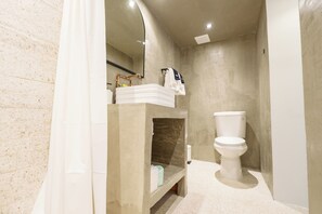 A bathroom with a toilet, a sink, and a shower curtain. - Romeo Hotel - Adults Only (San Juan)