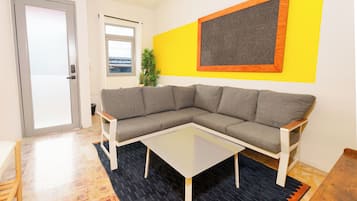 A modern living room with a gray sectional sofa, a glass coffee table, and a black rug.