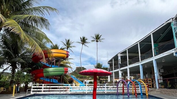 A swimming pool with water slides and palm trees. - Pousada Oásis do Sertão (Euclides Da Cunha)