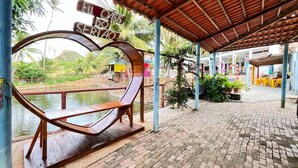 A covered outdoor area with a wooden bench, a water body, and a sign reading "EU OASIS SERATO". - Pousada Oásis do Sertão (Euclides Da Cunha)