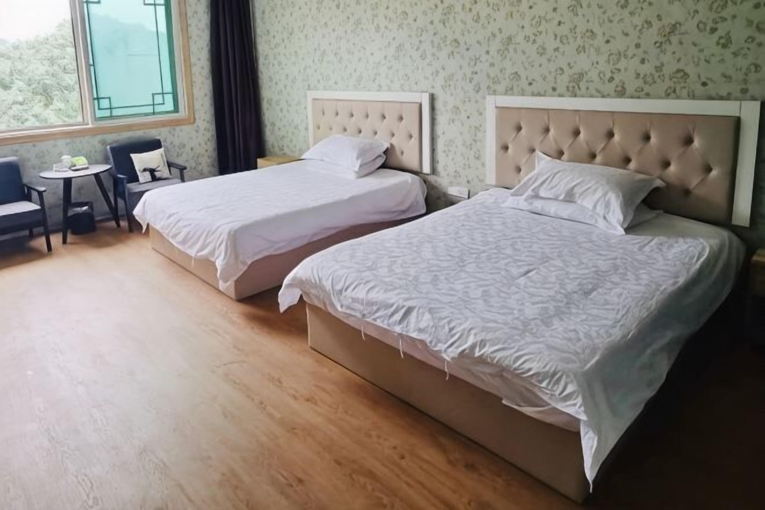 Habitación de hotel con dos camas, una mesita y una silla.