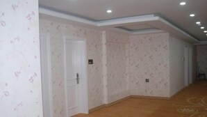 Un pasillo con papel tapiz estampado, una puerta blanca y suelo alfombrado.