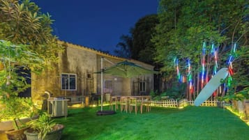 Una casa con patio trasero cercado, un patio y un árbol grande.
