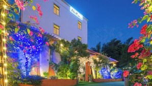 A building with a white facade, a garden with flowering plants, and a well-lit entrance. - Shenzhen Xinghai Xiaoye Inn (Shenzhen)