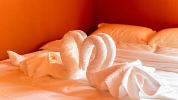 Una cama con sábanas blancas y una decoración de almohadas con forma de cisne.