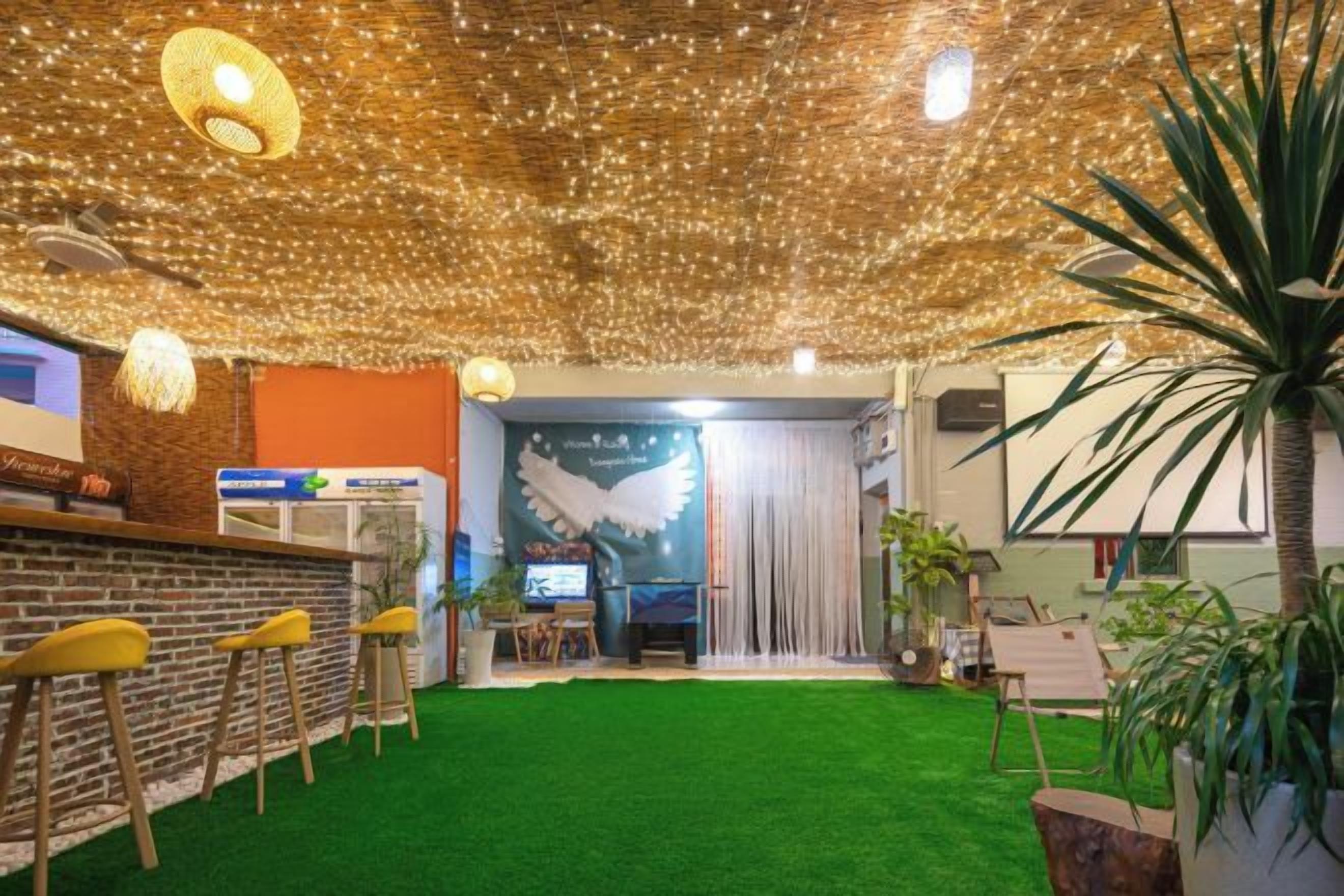 Una habitación con alfombra verde, pared de ladrillo y una zona de bar con taburetes.