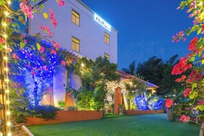 Um edifício com fachada branca, várias janelas e um gramado bem cuidado.
