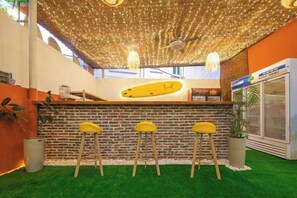 A reception area with a surfboard-shaped counter, green artificial grass, and a ceiling with string lights. - Shenzhen Xinghai Xiaoye Inn (Shenzhen)