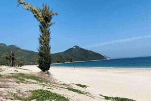 A beach with a clear sky, a sandy shore, and a mountain in the background. - Shenzhen Xinghai Xiaoye Inn (Shenzhen)