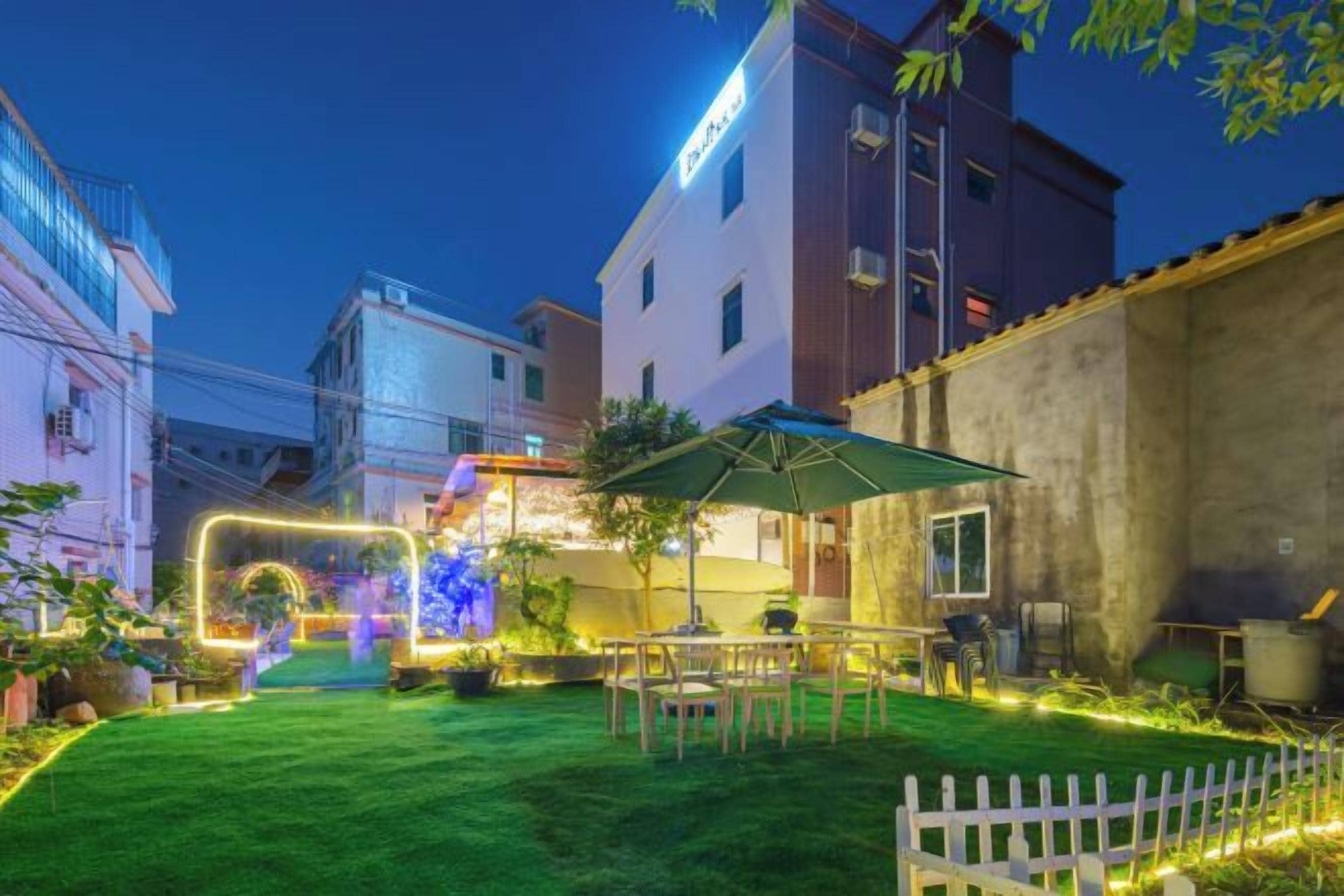 A courtyard with a lawn, outdoor seating, and a white picket fence.
