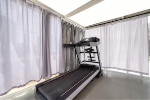 A room with a treadmill, large windows with curtains, and a tiled floor. - Hengsheng Hotel (Fuzhou Railway Station North Square) (Fuzhou)