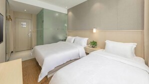 Une chambre d’hôtel avec deux lits, une télévision, une table de chevet avec une lampe et un mur vert.