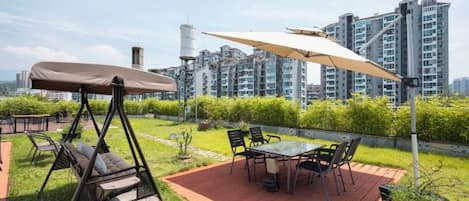 An outdoor patio with a swing, a table with chairs, and a large umbrella.