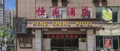 A hotel with a sign reading "HENG SHENG HOTEL" and a welcoming message in Chinese.