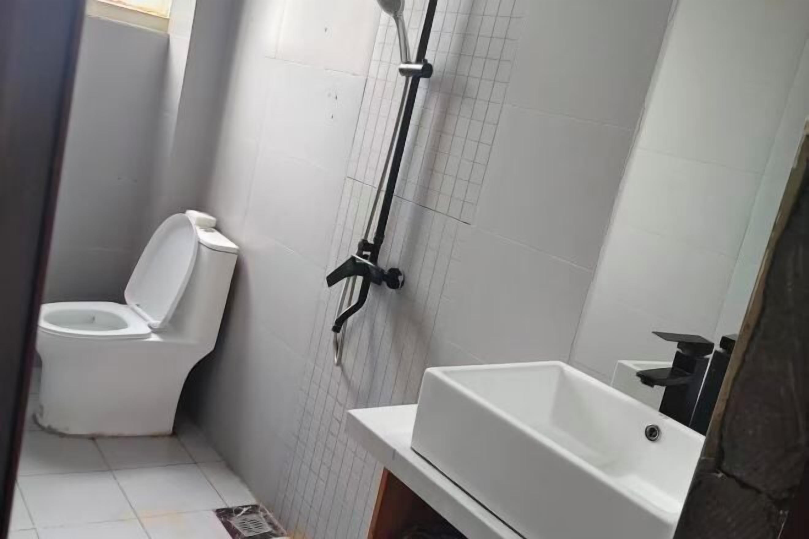 A bathroom with a toilet, a shower, and a sink.