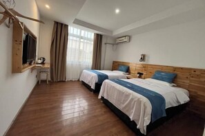 A hotel room with two beds, a wooden floor, a desk, a chair, a TV, and an air conditioning unit. - Yajiada Business Hotel (Tongren Railway Station Jinmatou) (Tongren)