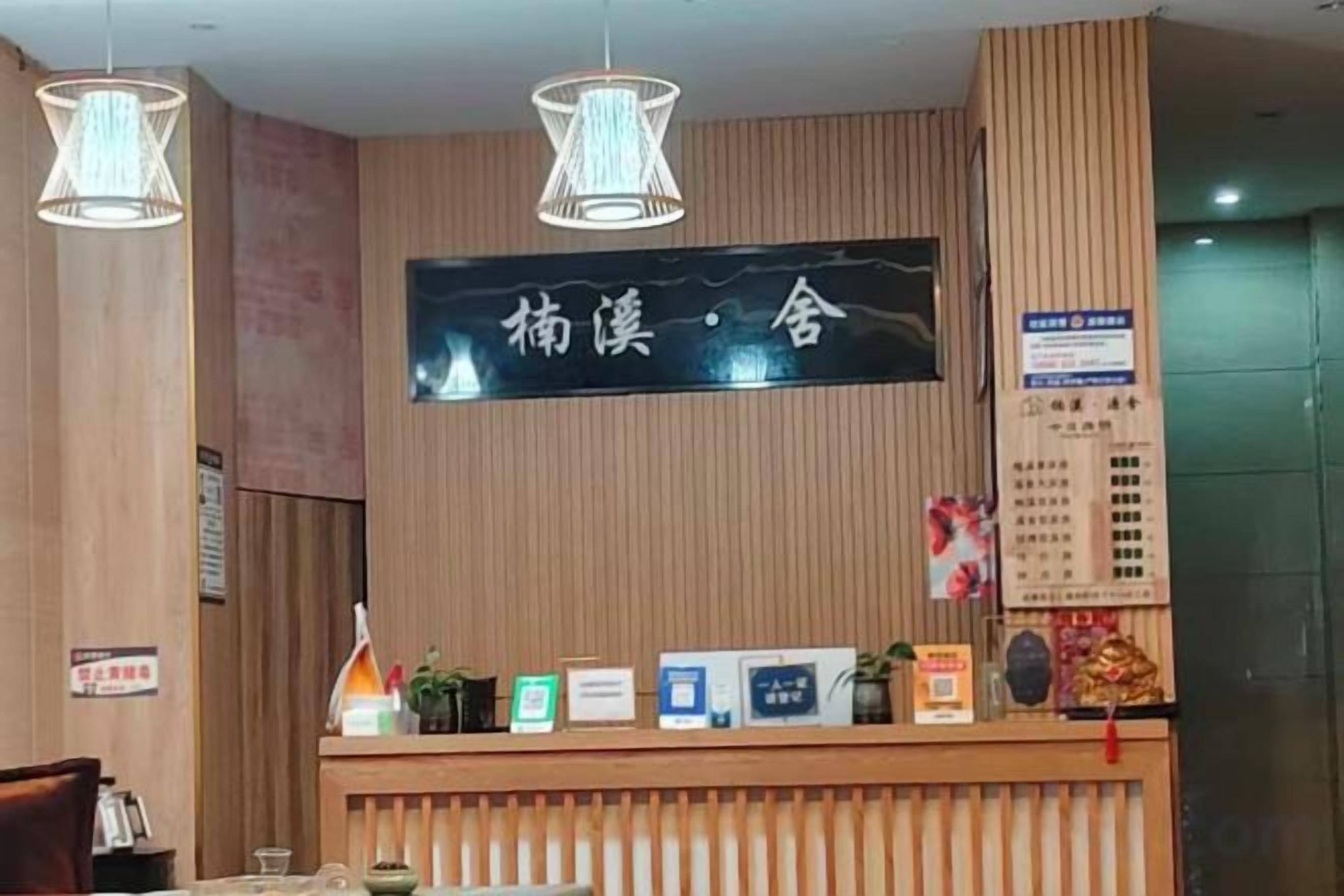 A reception desk with a wooden panel design, a black sign with white text, and a menu board on the right.