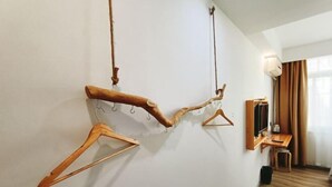 Ein Zimmer mit Kleiderhaken aussehen wie Holzäste, einem Schreibtisch mit Stuhl und einem an der Wand befestigten Fernseher.