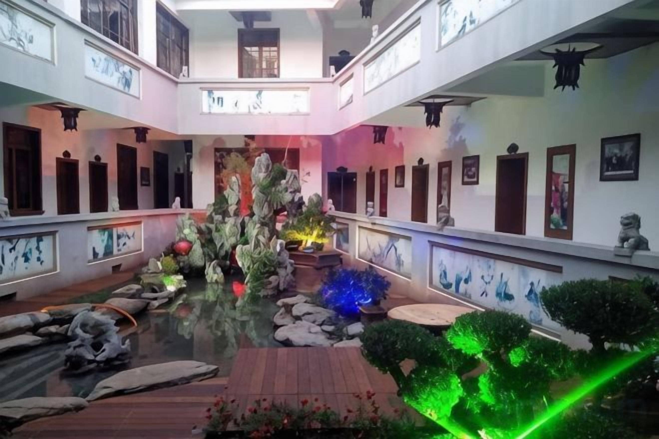A hotel lobby with a central water feature, multiple doors, and a balcony.