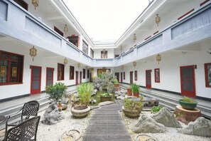 A courtyard with a central pathway, potted plants, and traditional red doors. - Maojia Hotel (Shaoshan)