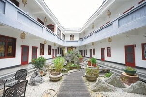 Un patio con un sendero central, plantas en macetas y puertas tradicionales rojas.