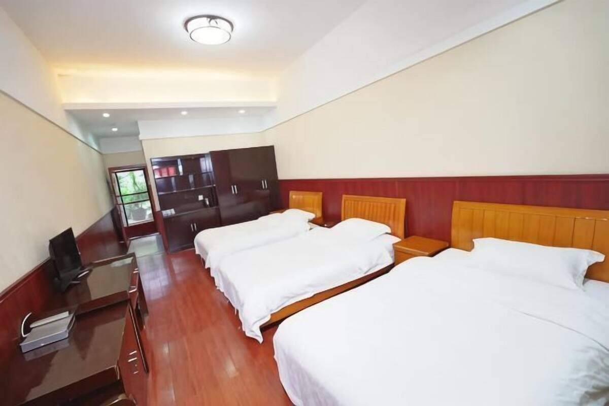Quarto de hotel com duas camas, uma escrivaninha, uma televisão e um guarda-roupa.