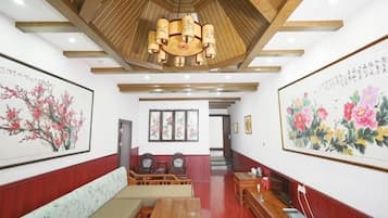 A hotel lobby with a wooden ceiling, a reception desk, seating area, and artwork on the walls.