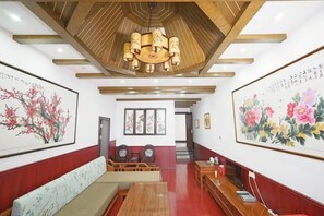Een hotellobby met een houten plafond, een receptiebalie, een zithoek en kunstwerken aan de muur.
