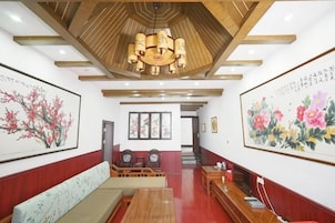 Un vestíbulo de hotel con techo de madera, un mostrador de recepción, zona de estar y obras de arte en las paredes.