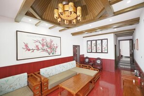 A traditional-style living room with a sofa set, wooden coffee table, and a large framed artwork on the wall. - Maojia Hotel (Shaoshan)