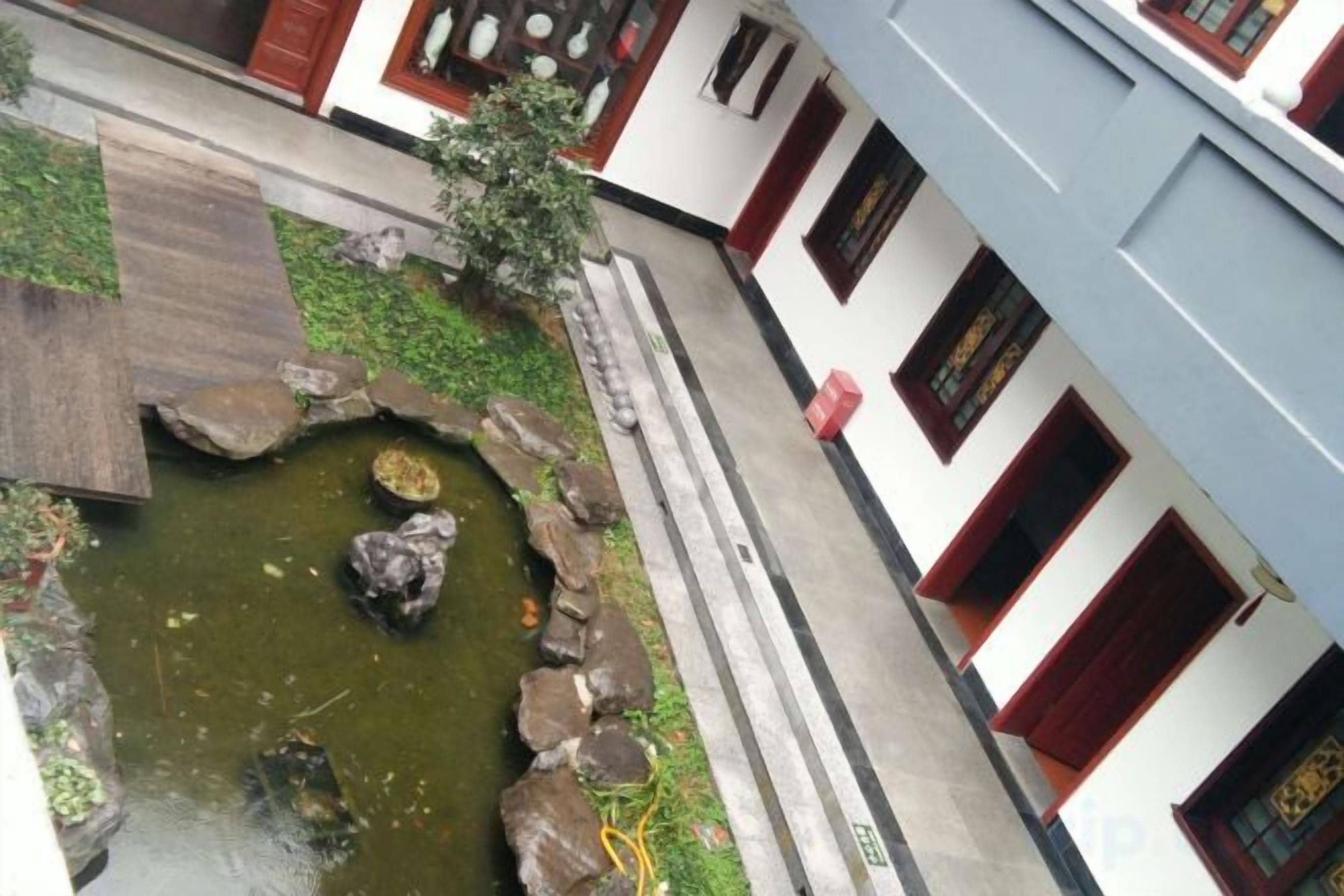 A courtyard with a small pond, stone pathway, and traditional architecture.